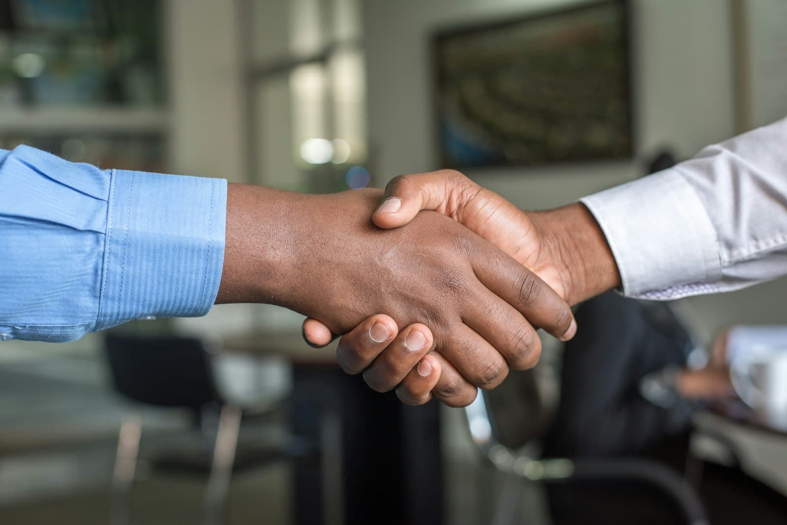 Two professionals shaking hands across a desk to close a funding agreement